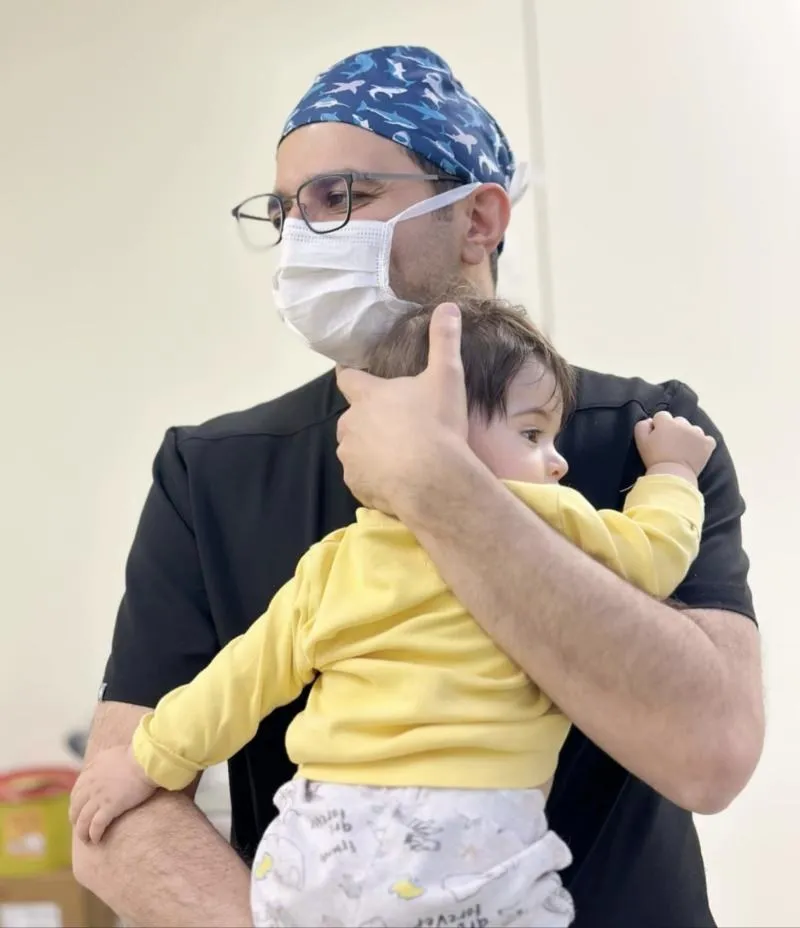 Pediatric urologist Dr. Parviz Hajiyev holding a baby in the operating room